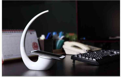 Stylish Phantom wireless charger lamp on a work desk, providing QI wireless charging and adjustable LED lighting for convenience.