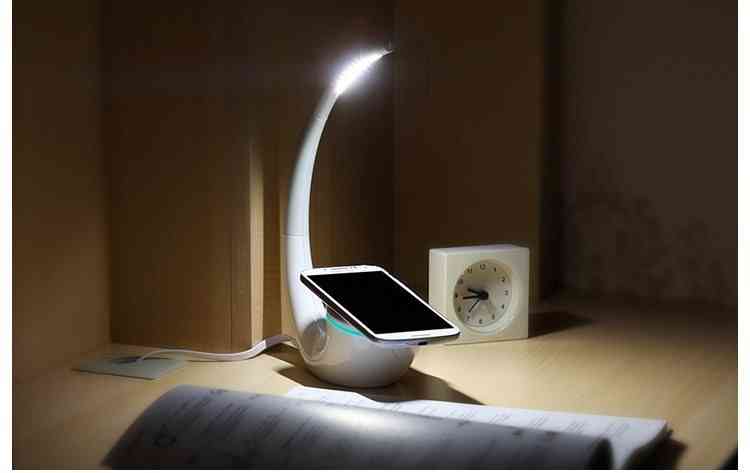 Elegant Phantom wireless charger lamp illuminating a study desk, offering stepless dimming and QI wireless charging for smartphones.