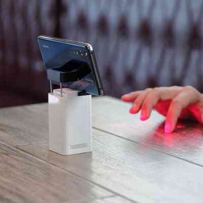 User typing on the projected laser keyboard of the LEING FST Virtual Laser Keyboard Bluetooth Projector while connected to a smartphone.