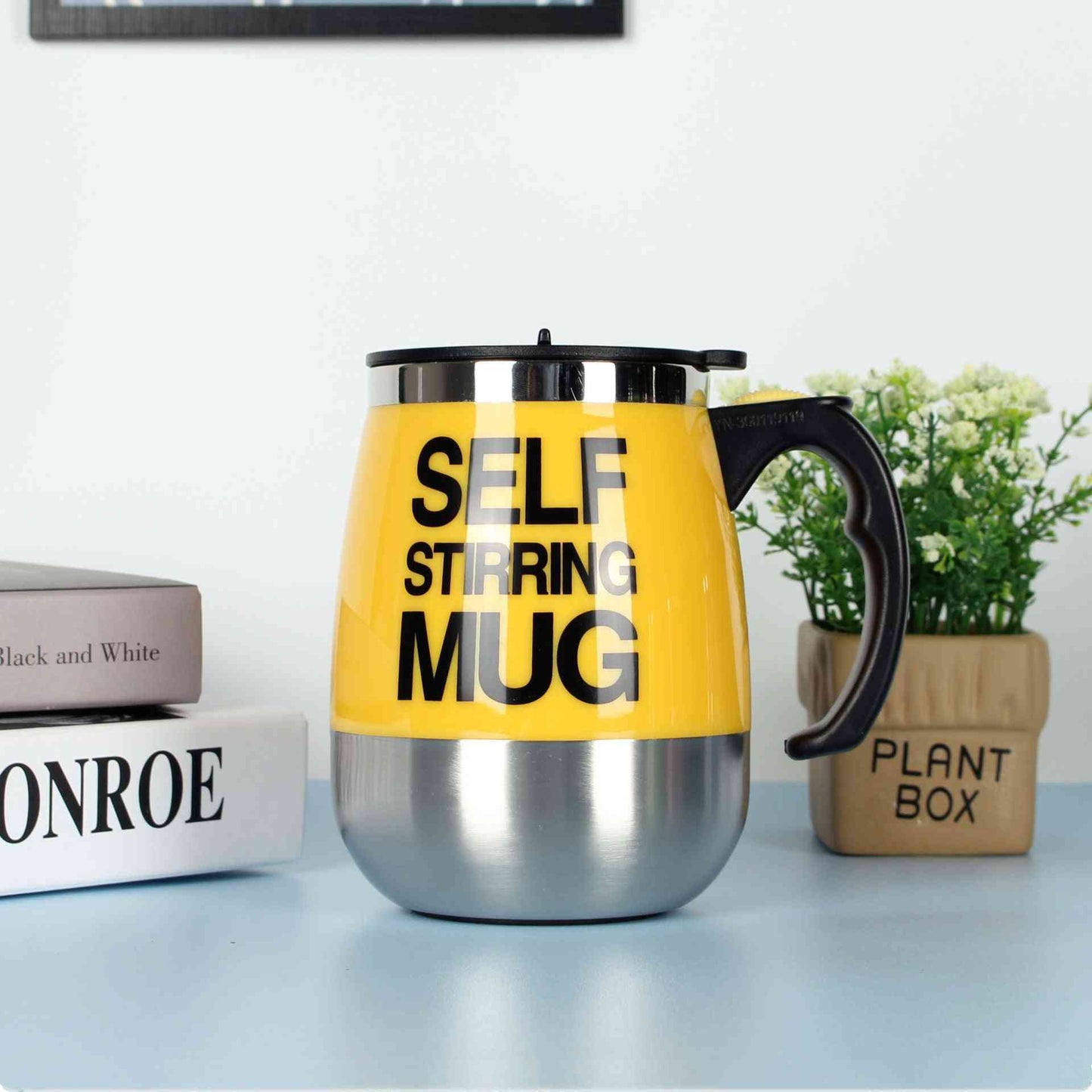 Yellow self-stirring electric coffee mug with stainless steel base and black handle, designed for easy and automatic mixing of drinks.