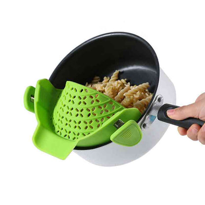 Green silicone pot side drain attached to a saucepan, straining pasta efficiently for a hassle-free cooking experience.