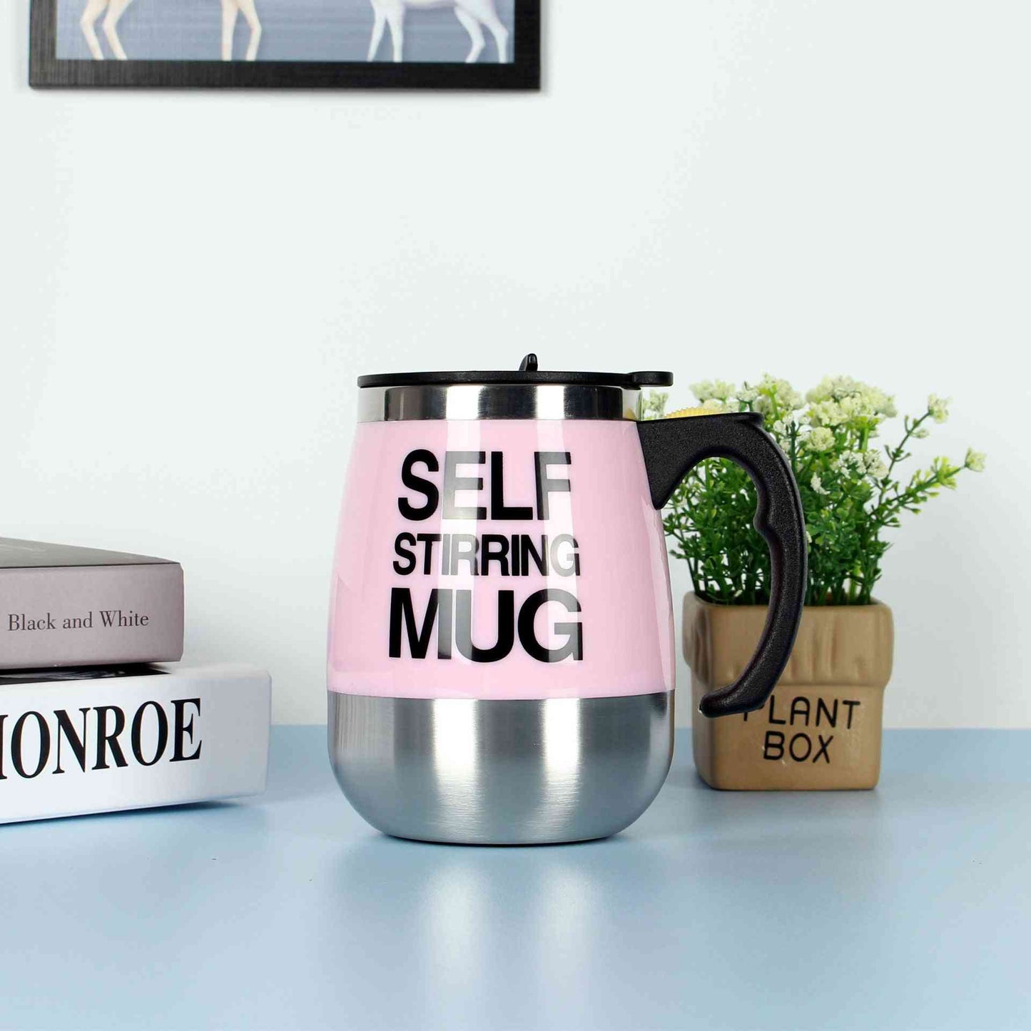 Pink self-stirring electric coffee mug with stainless steel base and black handle, perfect for home or office use.